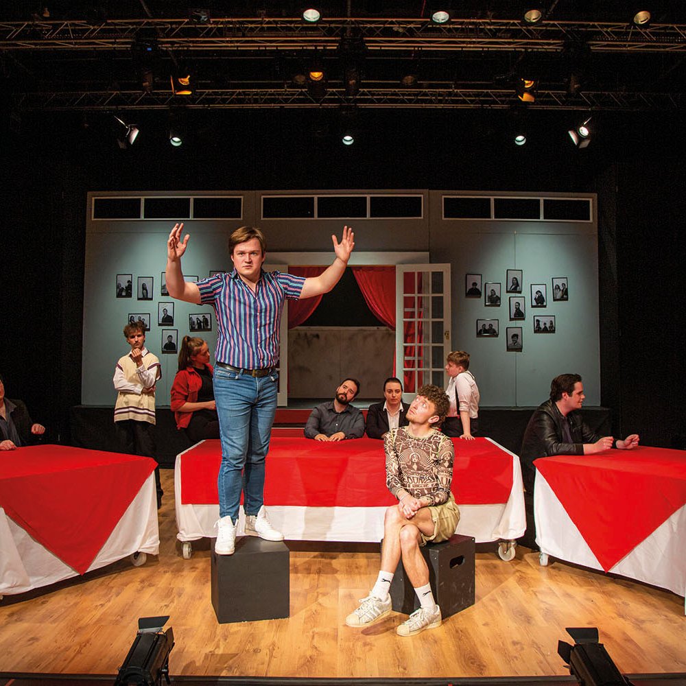 Student stood on a box on stage with arms open