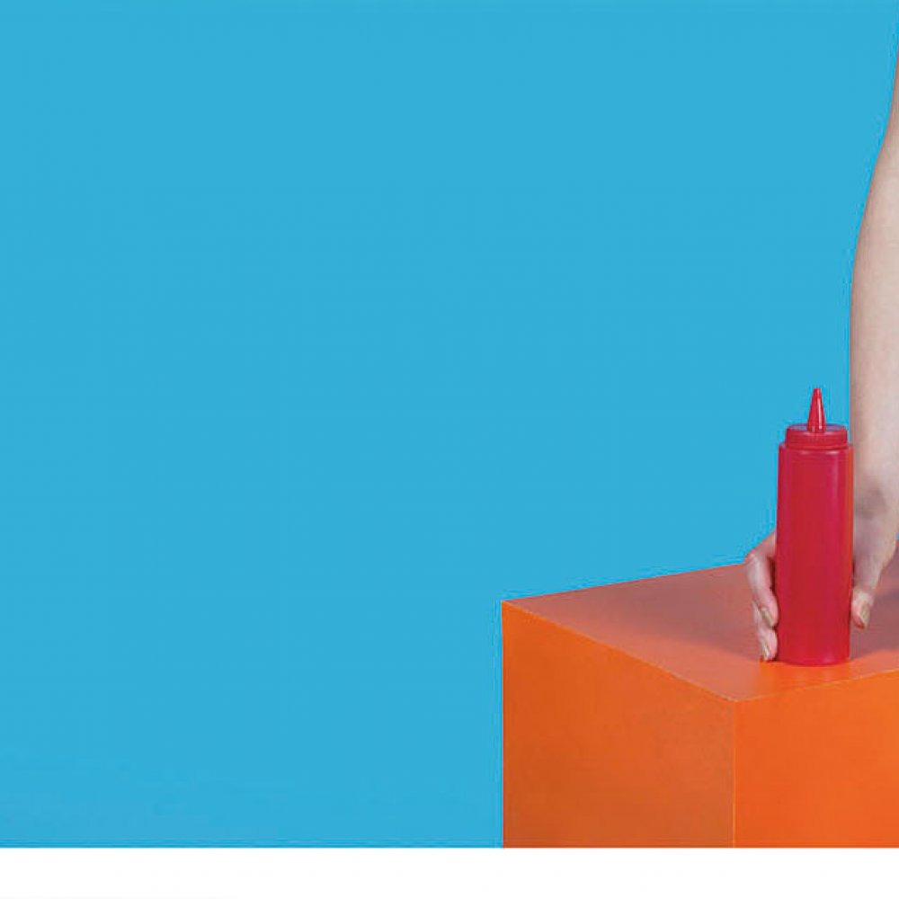 Brightly dressed female holding ketchup bottle