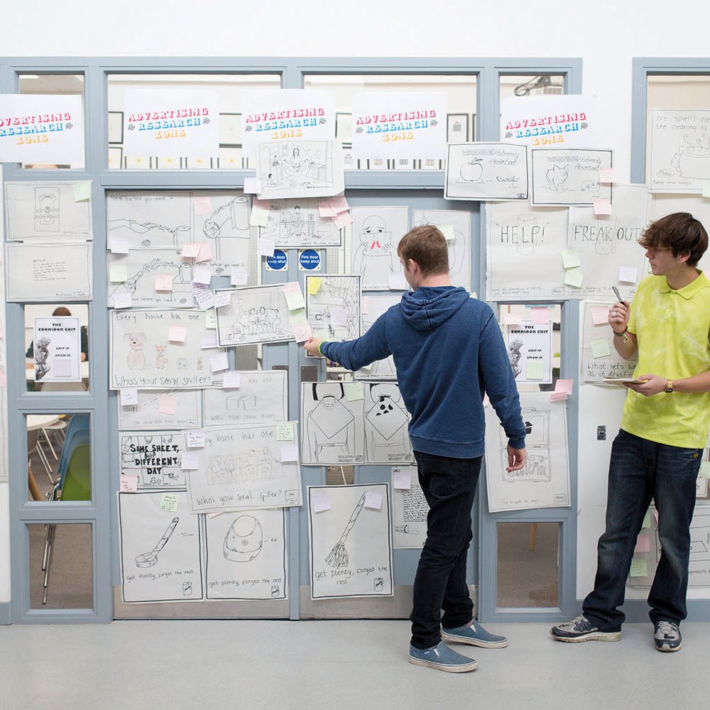 Students standing at a wall full of ideas written on paper
