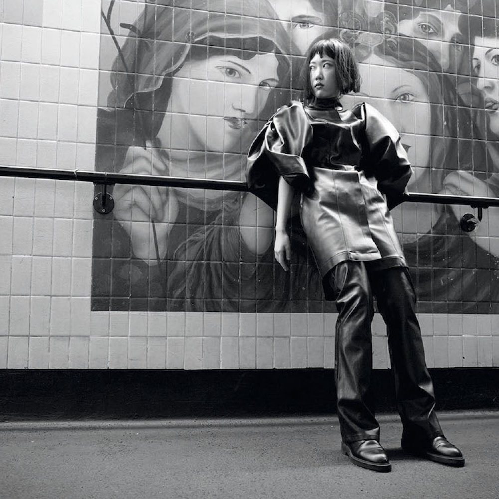 Fashion model posing in front of a mural of pre-raphelite women