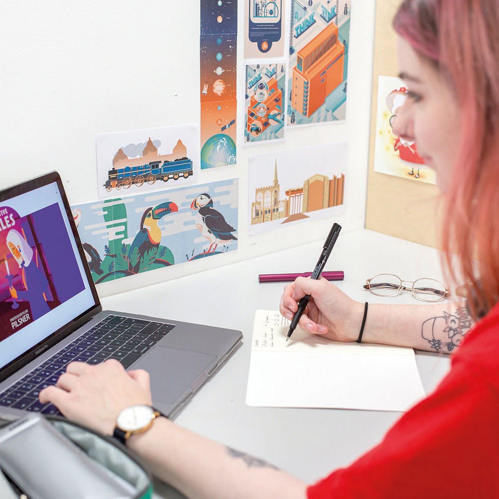 Student looking at laptop and drawing