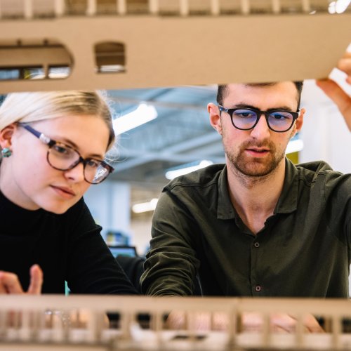 Interior design students looking inside a model.