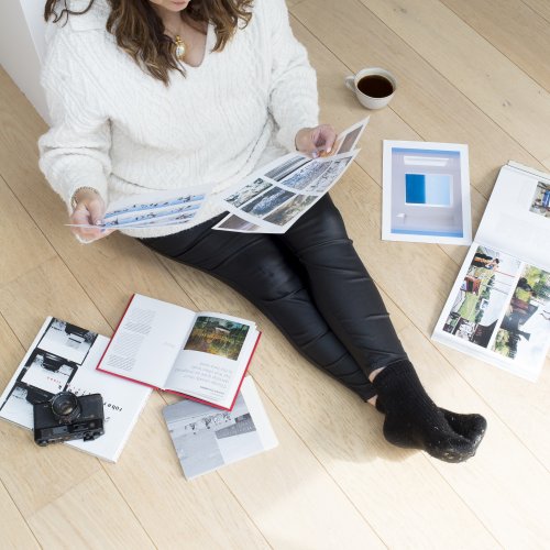 An online photography student sat on the floor with their work
