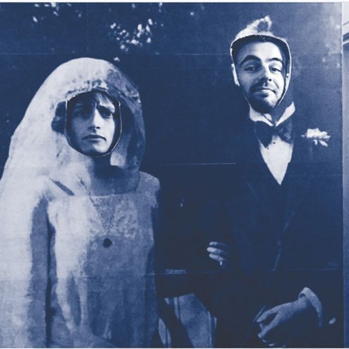 Black and white photo of two men with their heads showing through a life sized photo of bride and groom.