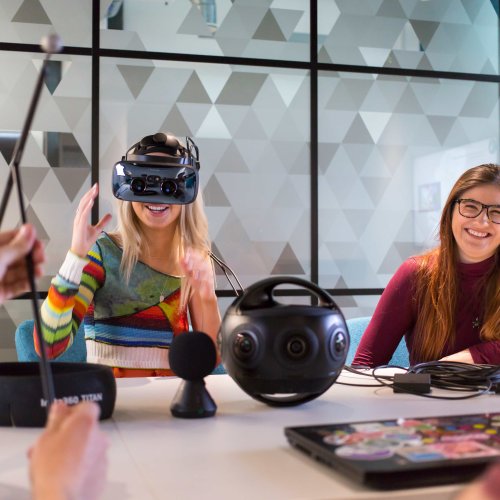 Two Falmouth University students at a table, one wearing a VR headset