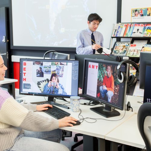 a male and female student in an IT suite with magazines on a shelf