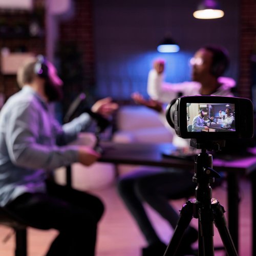 View of SLR camera filming two people in conversation around a table