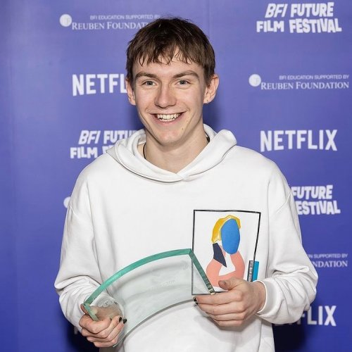 Will Wightman - dressed in a white hoodie - poses with his Best Director Award