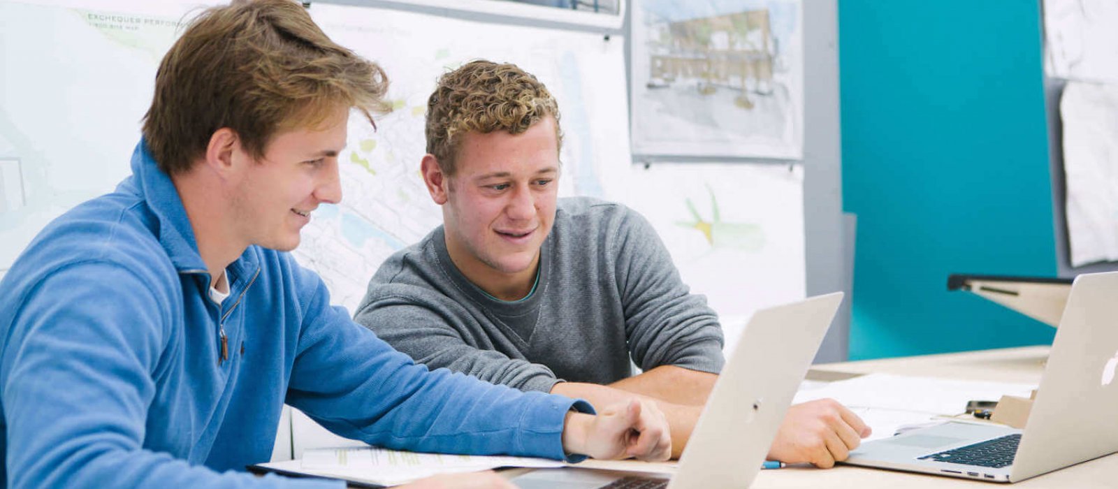 Two male students seated while looking at a laptop