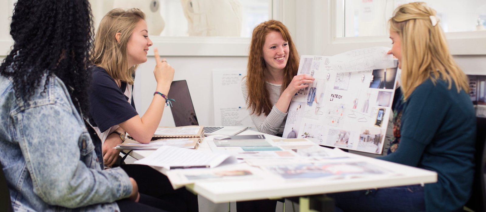 Falmouth University students discussing work on boards in a studio.