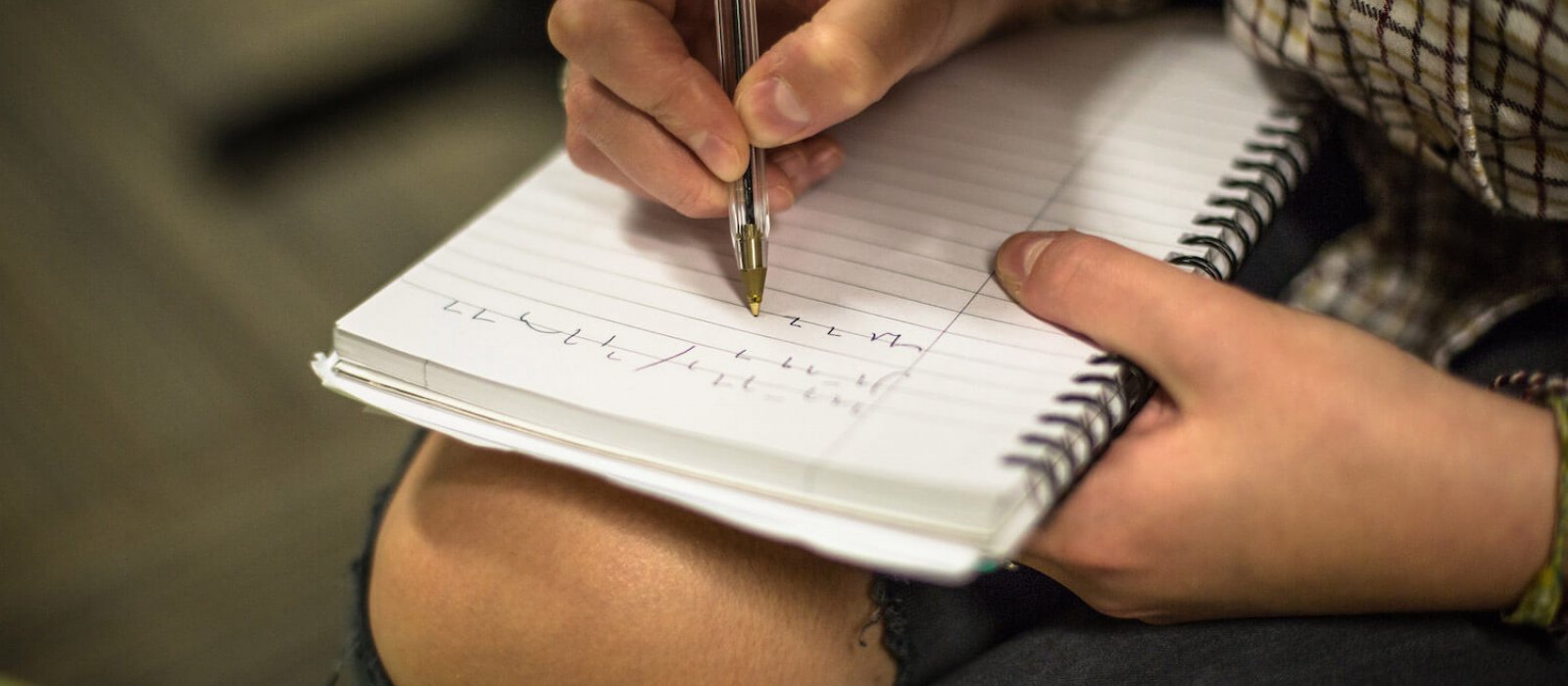 A person writing on a notepad with a biro