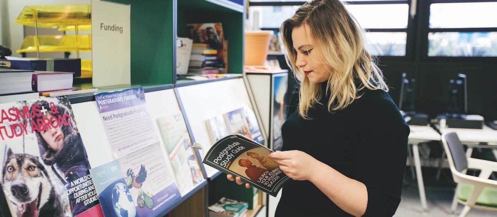 A Falmouth University student looking through a Postgraduate study guide