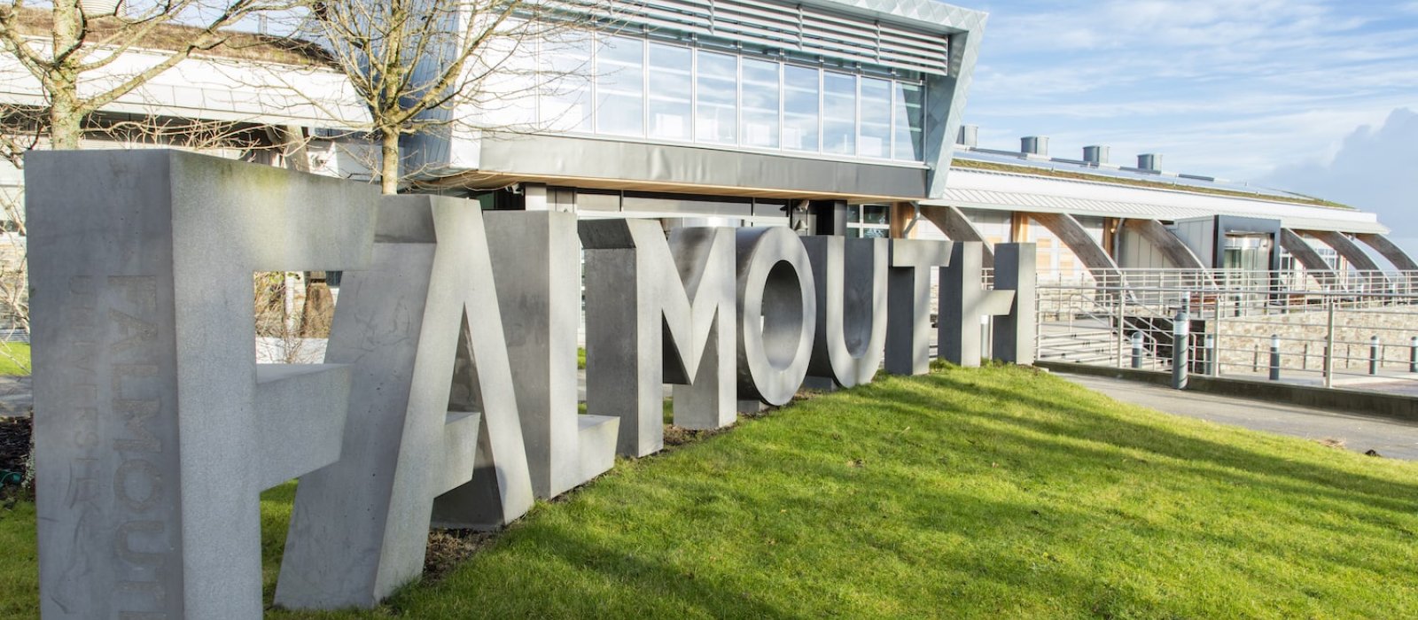 Falmouth University concrete sign in front of glass building