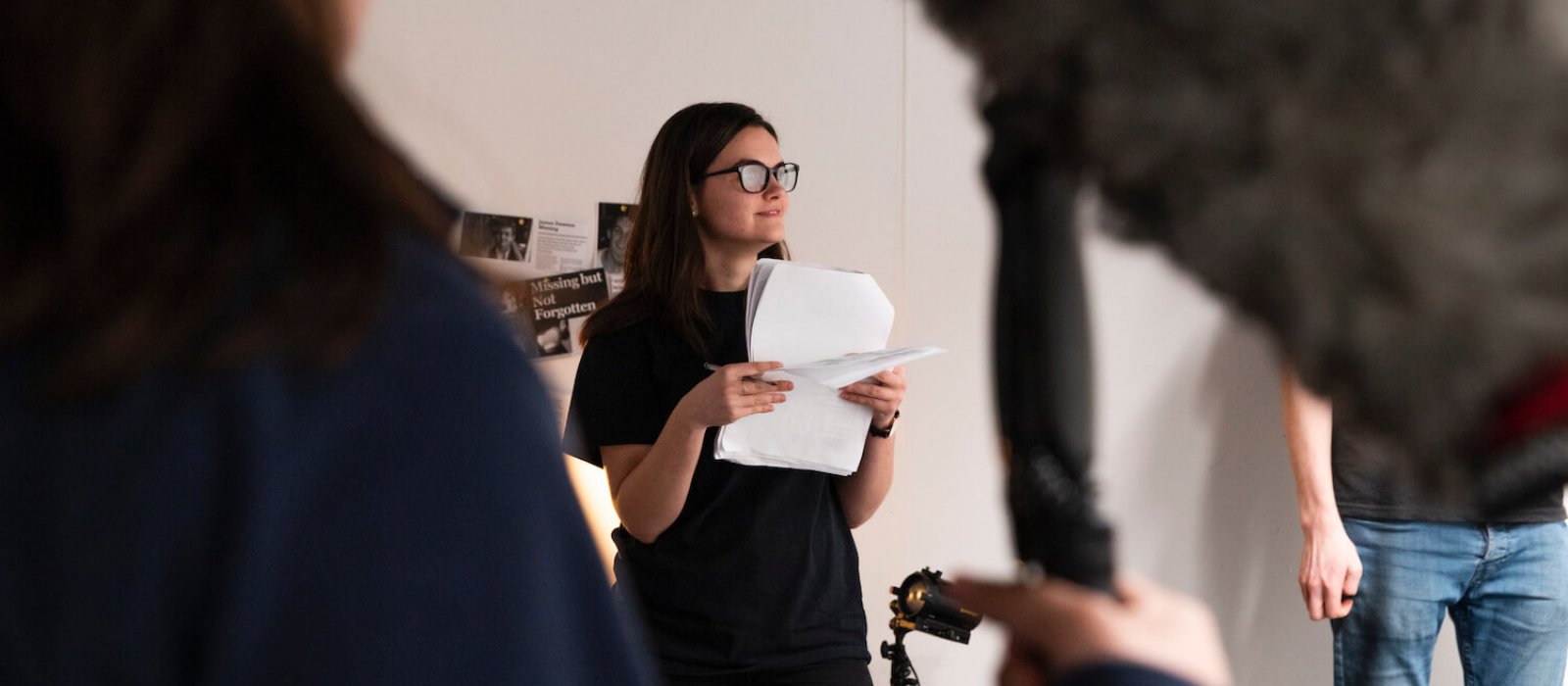 Film student standing holding pieces of paper