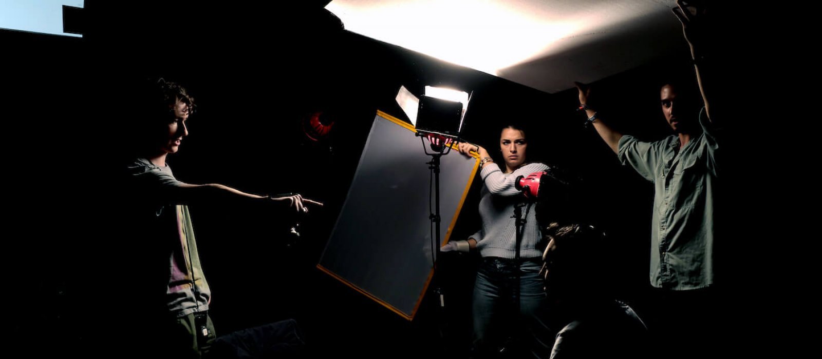 Falmouth Film students holding up reflectors in dramatically lit studio