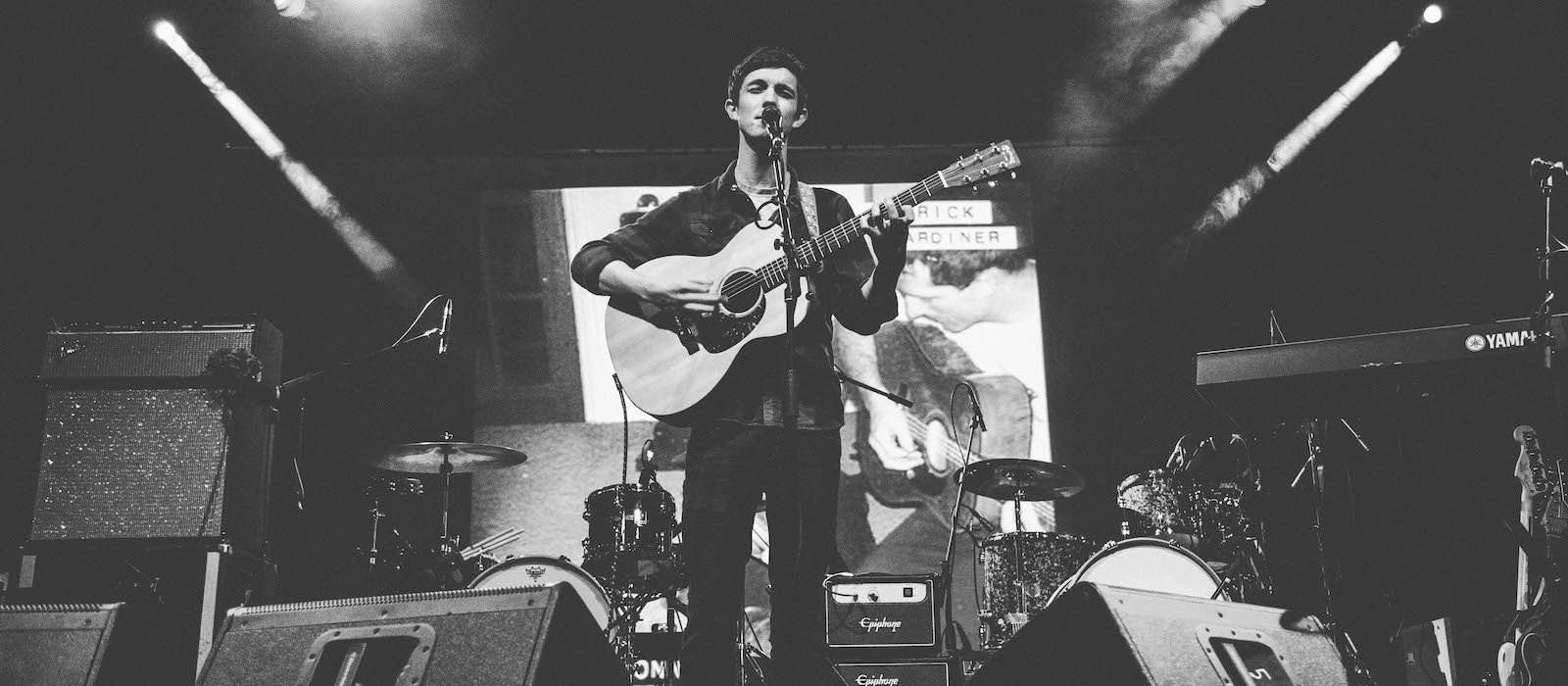 Falmouth University music student on stage playing guitar.