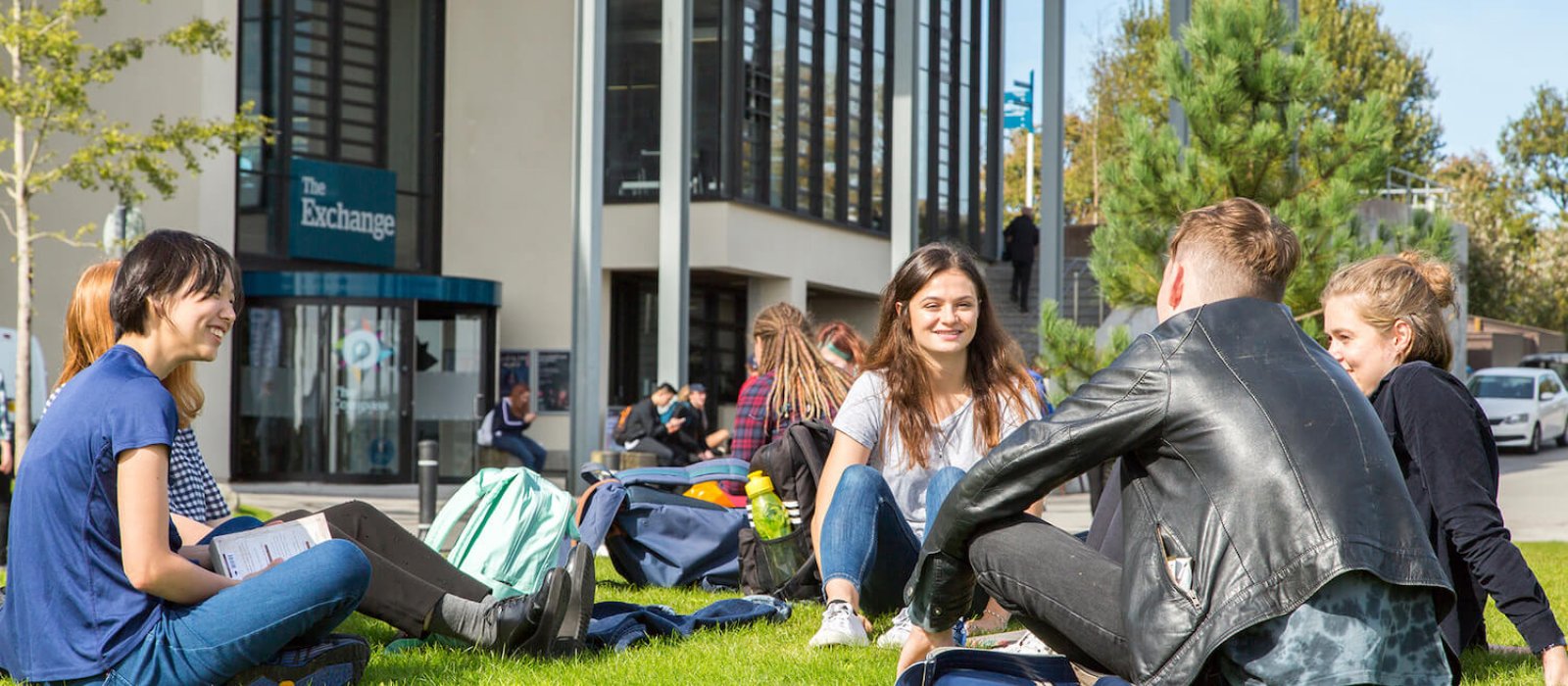 Penryn campus students outside exchange, sitting on grass