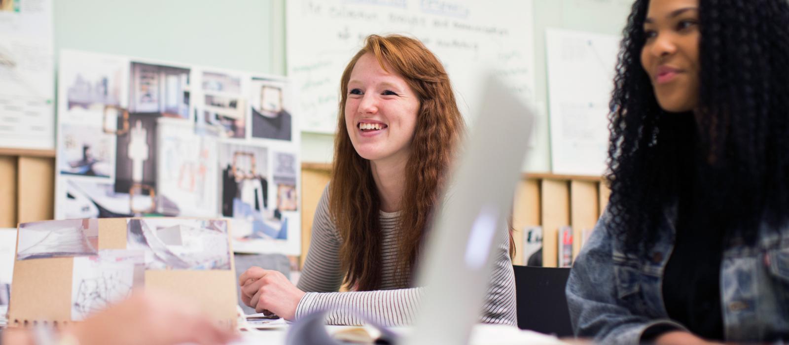 Smiling fashion marketing students working together around a desk.