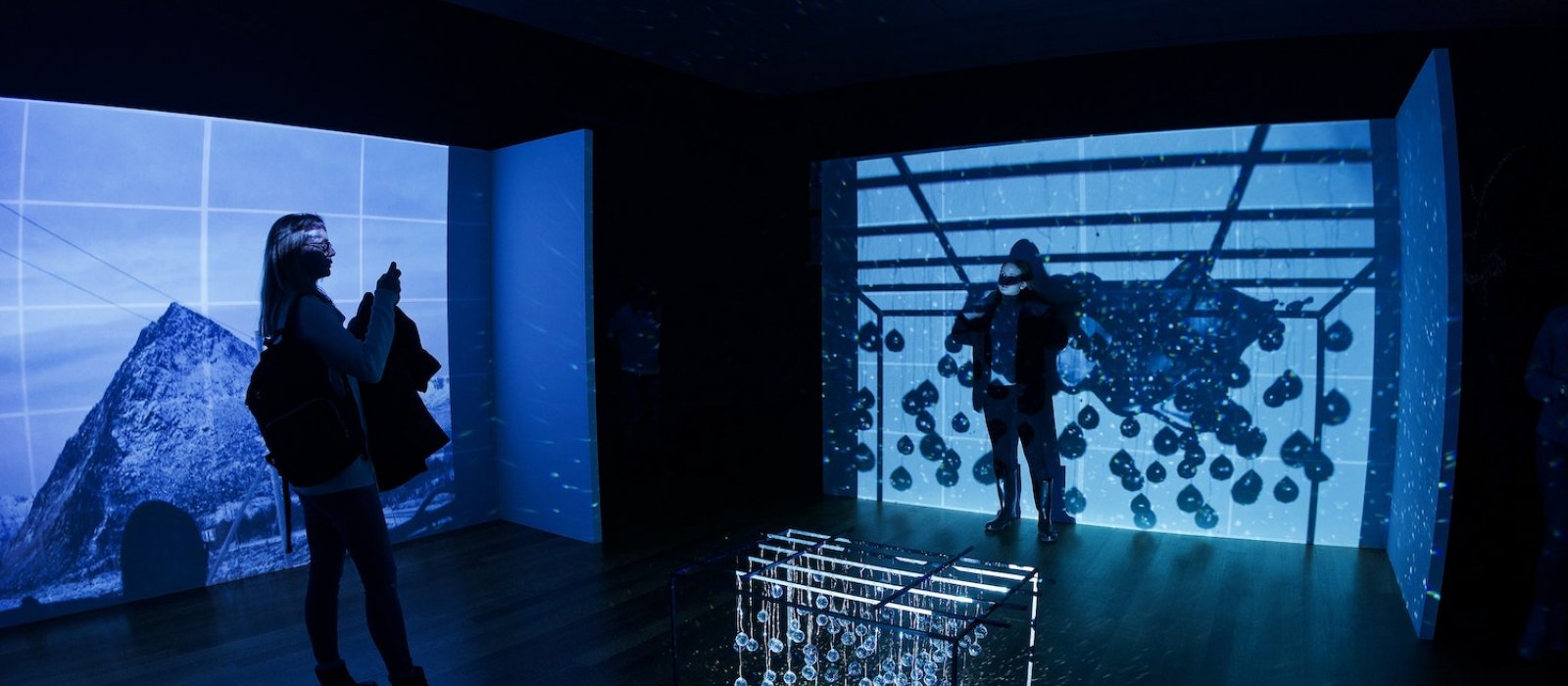 Two people standing in a dark room with blue projections