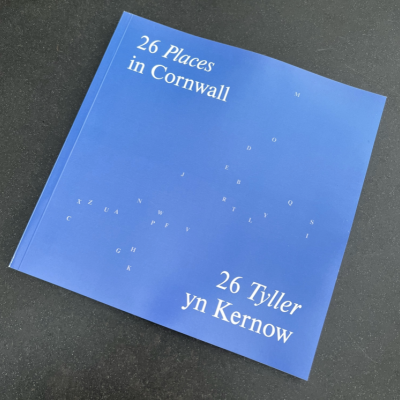 Photo of 26 Cornwall book - light blue cover with A-Z of letters scattered in the shape of Cornwall in white. Title reads: 26 places Cornwall / 26 Tyller yn Kernow