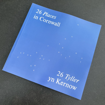 Photo of 26 Cornwall book - light blue cover with A-Z of letters scattered in the shape of Cornwall  in white. Title reads: 26 places Cornwall / 26 Tyller yn Kernow