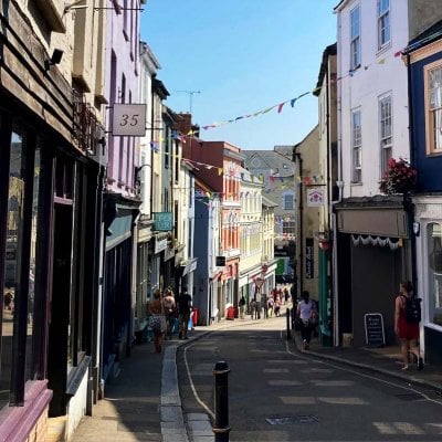 An image of shops on the Falmouth high street, bathed in sunlight