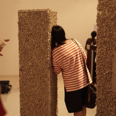 A student leans against a pillar-like sculpture covered in beige bobbled fabric, Falmouth University, Cornwall