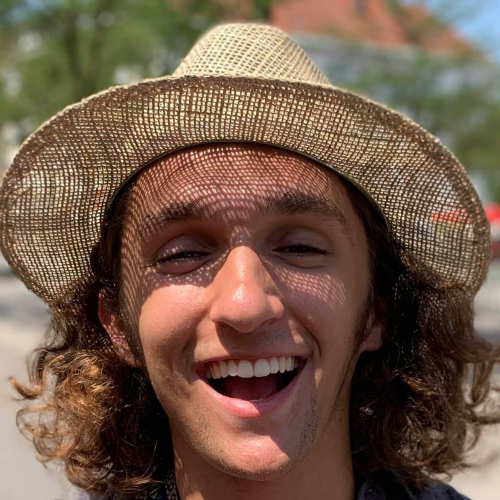 Falmouth University student smiling, wearing a straw hat