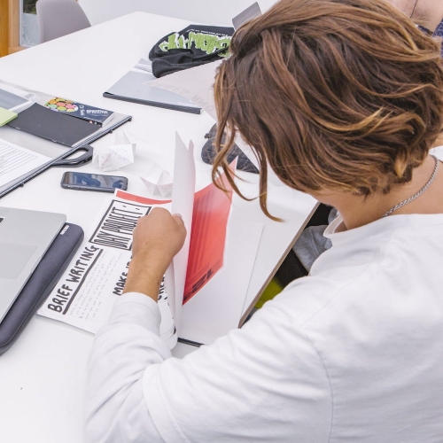 Graphic Design - professional practice week Graphic Design student at a laptop with papers