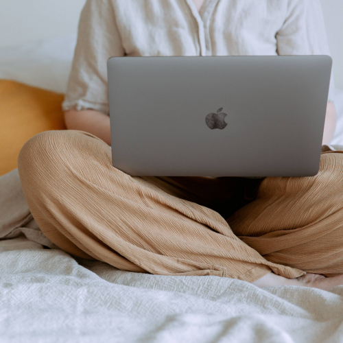 Online Study A person sat crossed legs with an apple mac and a cup