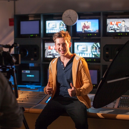 Student giving the thumbs up in television control studio.