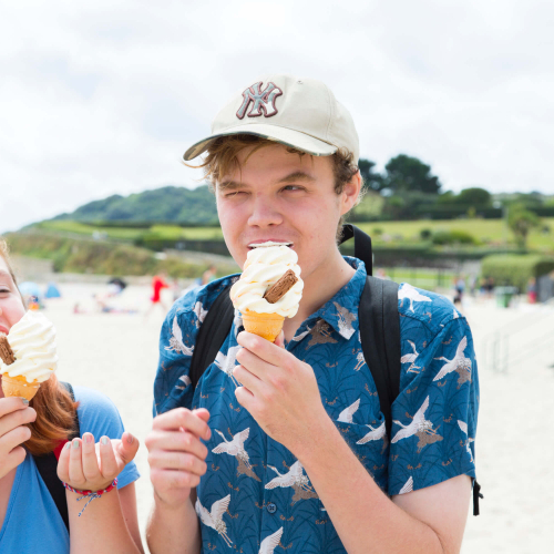 Two Falmouth University students eating ice creams on the beach