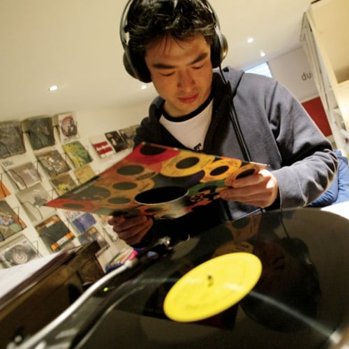 Student wearing earphones and putting record on record player.