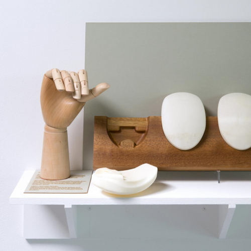 Wooden hand on display next to white oval shapes.