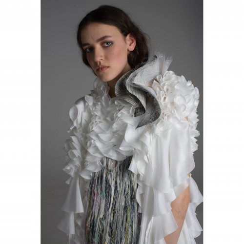 Model wearing white and grey frilly shirt with tassels at the front.