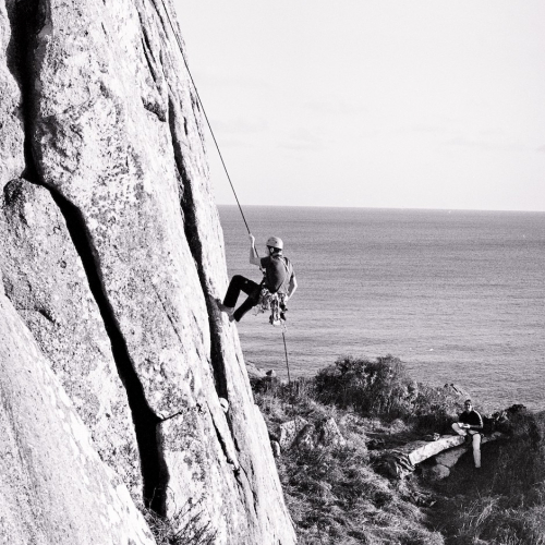 Falmouth University student climbing up a cliff face