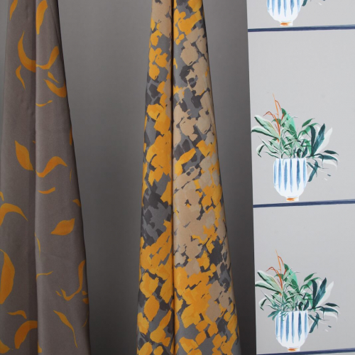 Grey and yellow fabrics and wallpaper with a green plant design.
