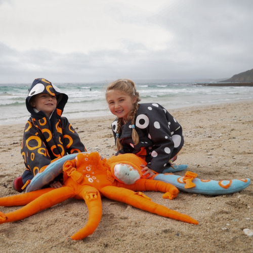 Two young children on the beach with a star fish toy