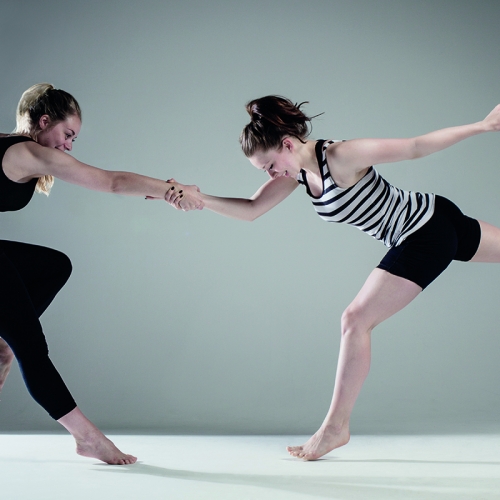 Two dancers in handshake hold and one leg extended and one leg bent