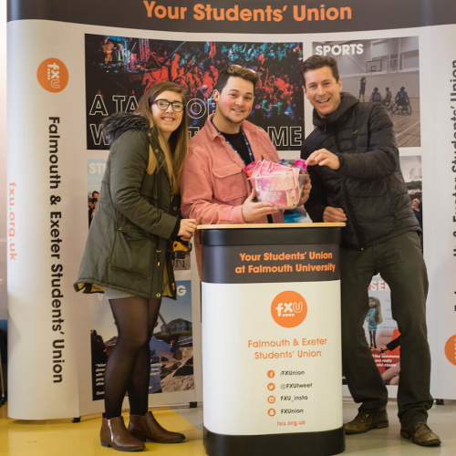 Students from Falmouth's student union posing at their stand at an event.