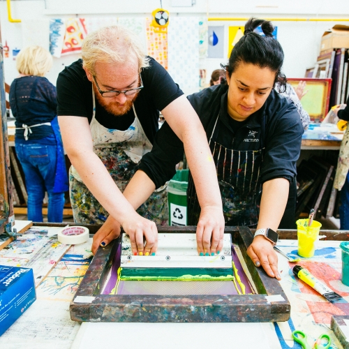 Two people screenprinting in a workshop