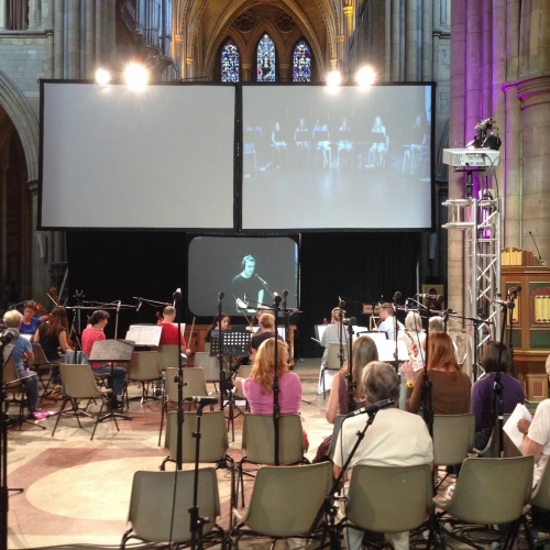Group of people playing musical instruments in front of screens in a cathedral