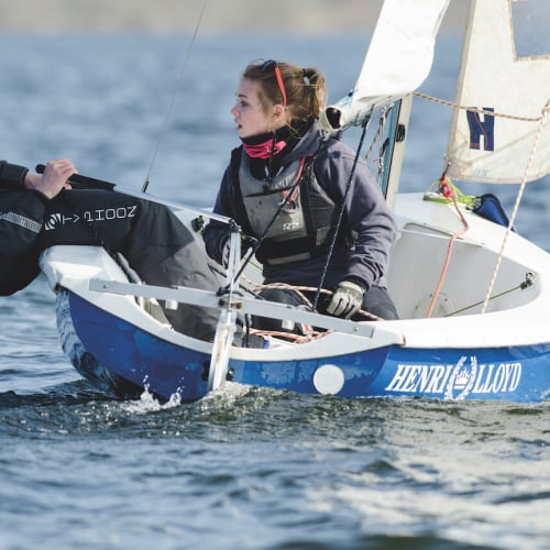 Falmouth University student diving backwards out of a sailing dinghy.