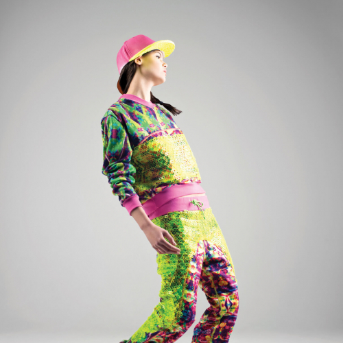 Model in bright coloured and patterned tracksuit with pink and yellow baseball cap.
