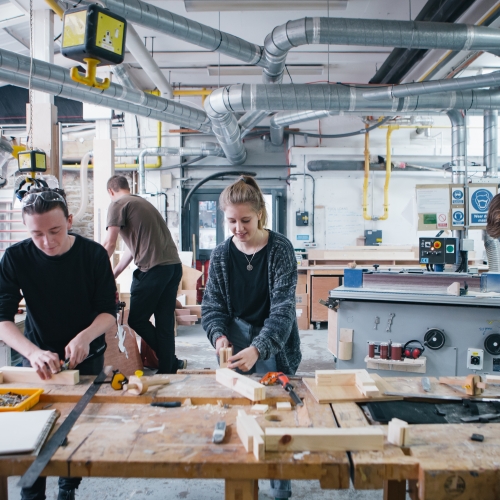 Female student and two male students in wood workshop